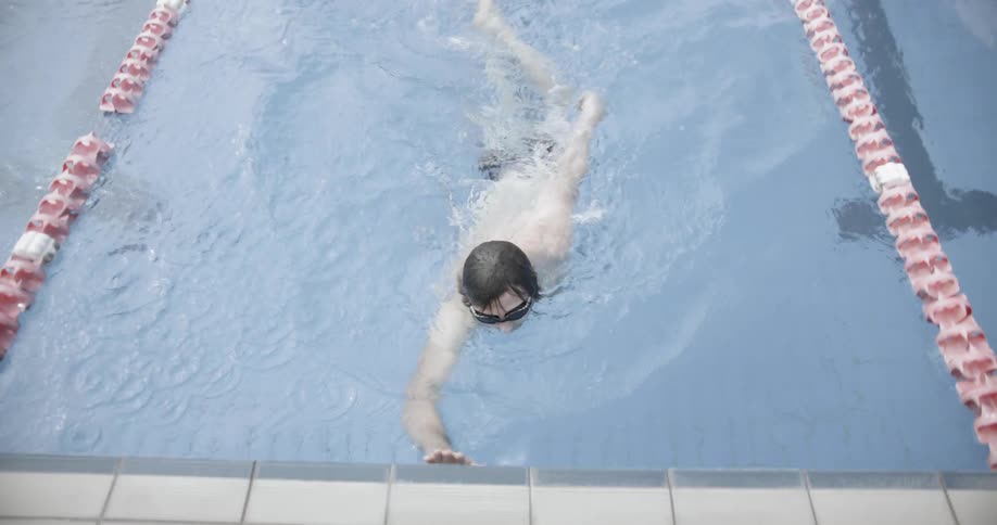 Man swimming in his lane in a pool comes to the edge and removes his goggles