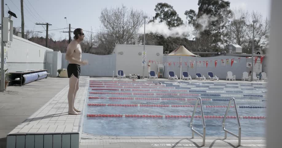 Man puts goggles on and dives into a swimming pool outside