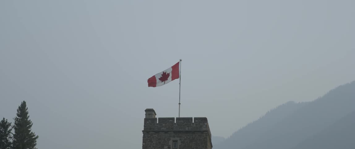 A canadian flag waves from a top a stone structure