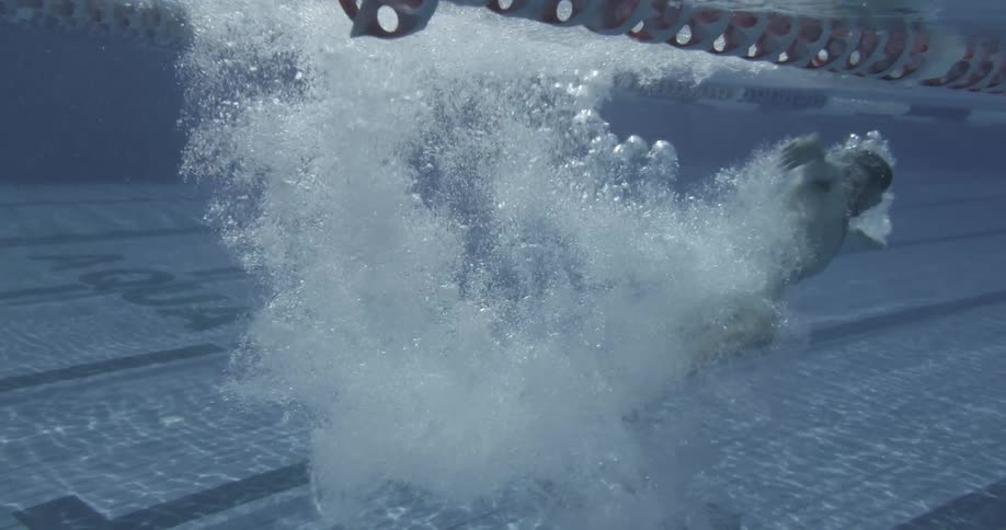 A man is diving into a swimming pool and swimming