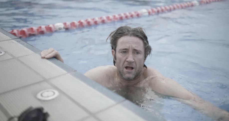 A man takes off his goggles and pulls himself out of the pool