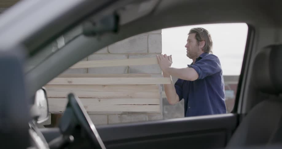 A man pulls a piece of lumber from a stack