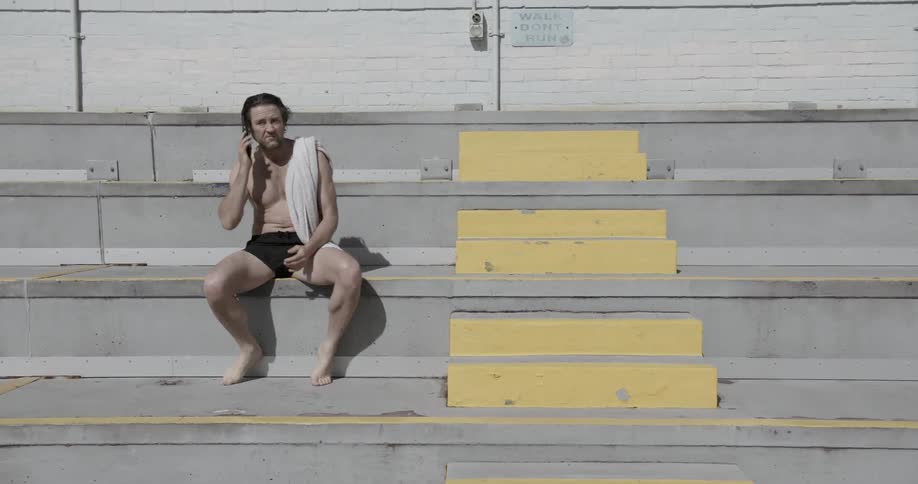 A swimmer answers the phone on outdoor bleachers