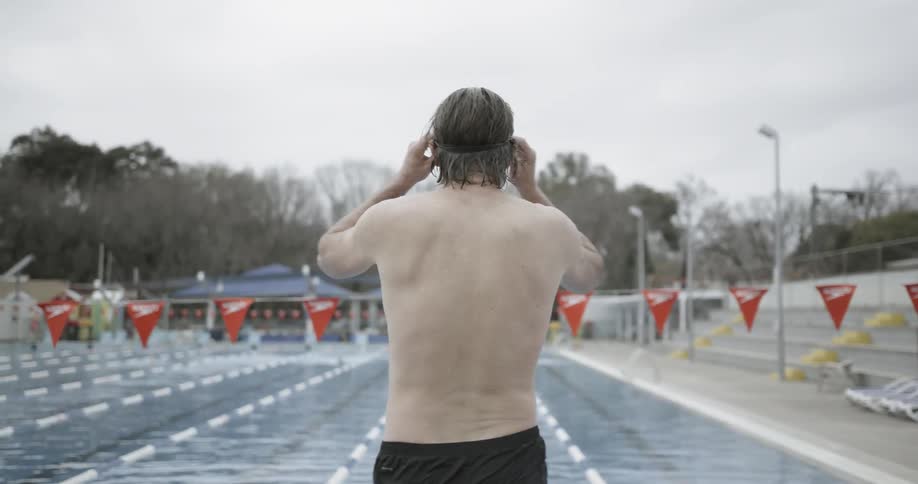Man puts on goggles and jumps into a swimming pool