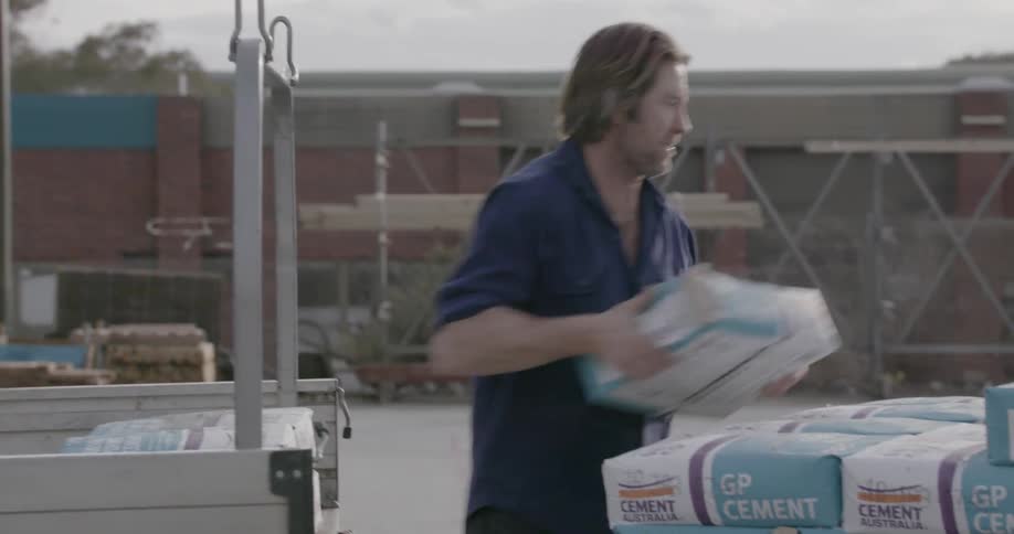 A man is guiding a forklift and then stacking bags on it