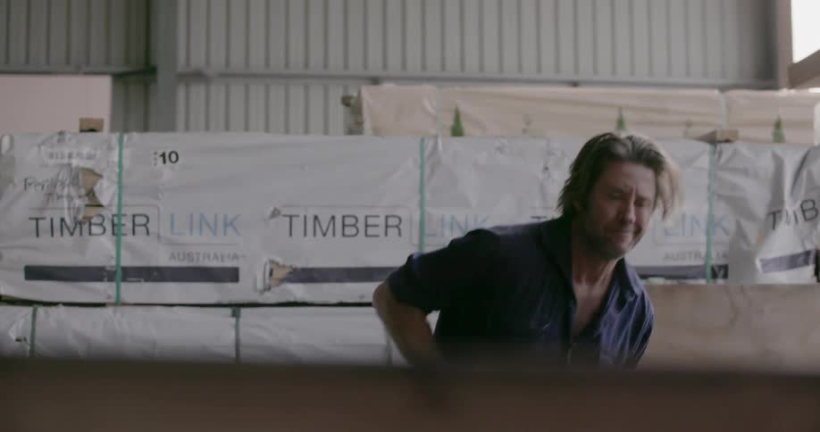 Man carries lumber in a warehouse