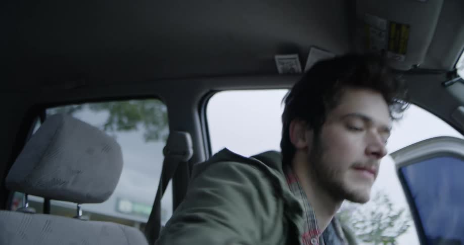 A man is getting into an suv at dusk and talking to himself