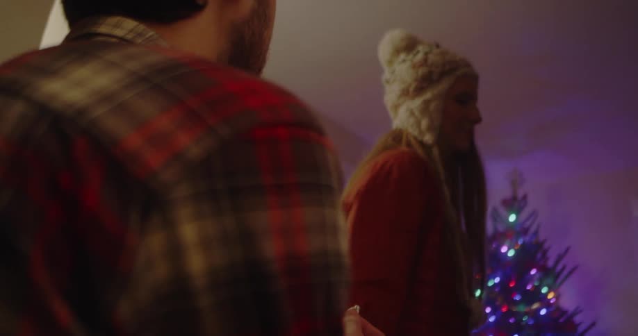 A man proposes to a woman next to a christmas tree
