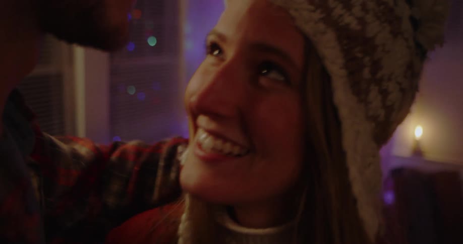 A man and woman embrace in front of the christmas tree