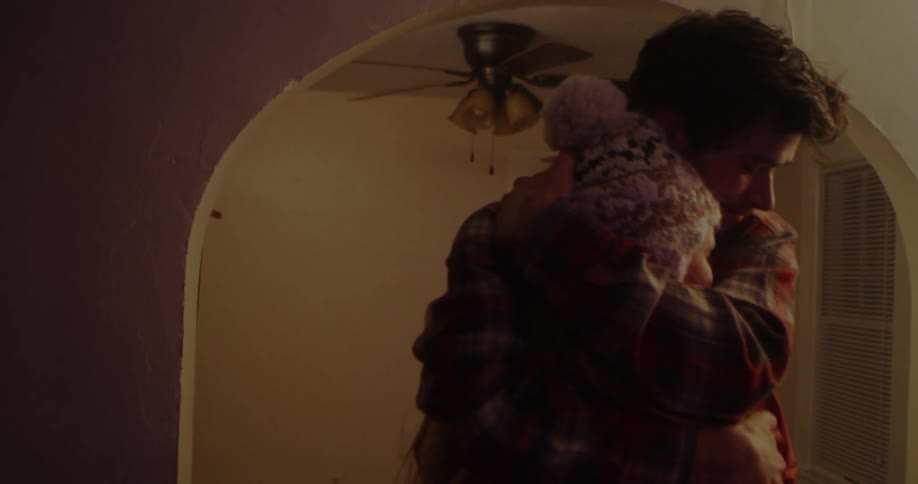 Man and woman hug each other in a dim room
