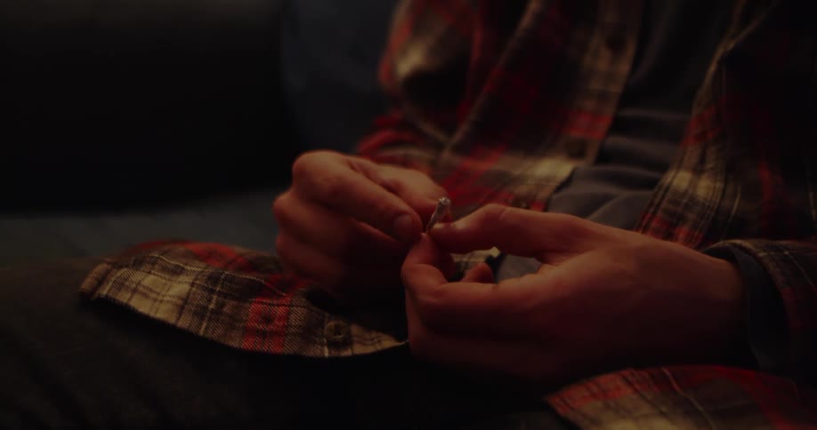 A man is fiddling with the engagement ring he holds his hands