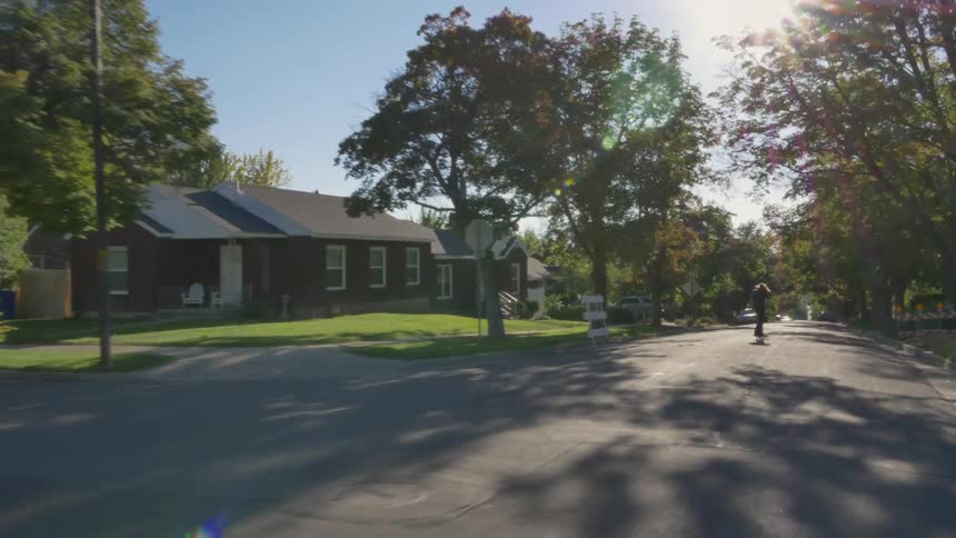 A person skateboards through a neighborhood