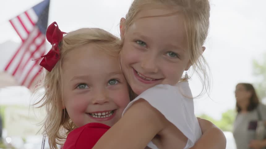 Two girls smile and hug each other