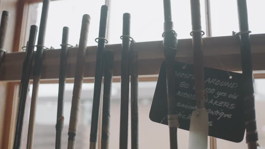 Row of wooden poles stood up in a row on a rack next to a window