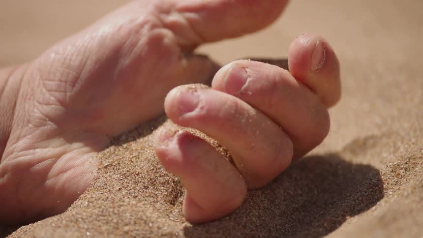 Sand sifts through a man's hand