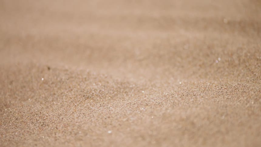 Grains of sand drift and blow in daylight