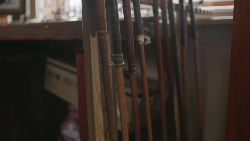 Antique golf clubs lean in a rack in a store