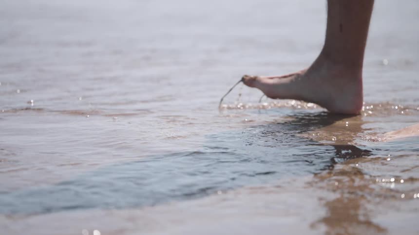A person walks into the shallow water