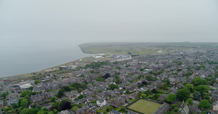 Fog and clouds are lingering over a coastal community during the day