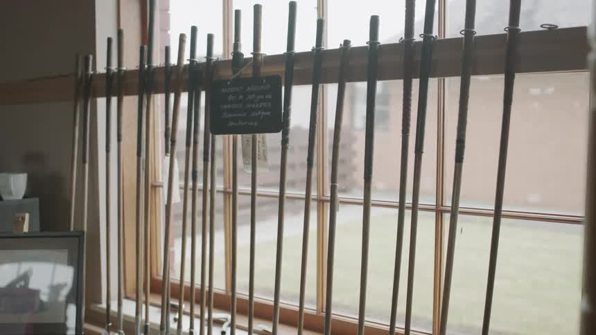 Golf clubs are lined up in a display in a window during the day