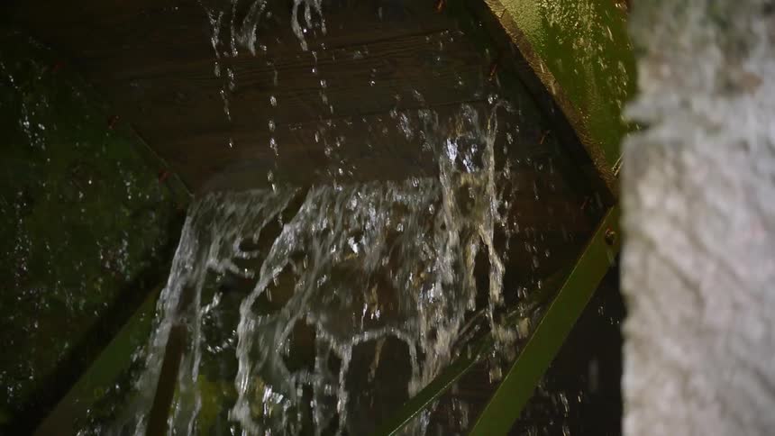 A water wheel is turning in an old mill during the day