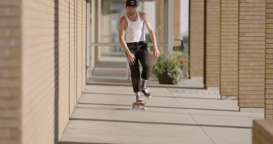 A person skateboards on a sidewalk in the daytime