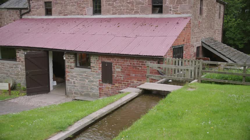 Water flows by a rural brick building