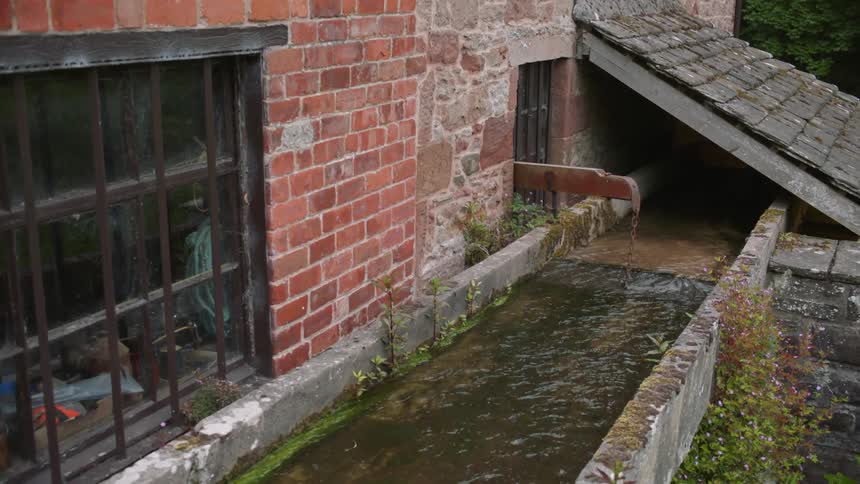 Water flows outside of an old brick building