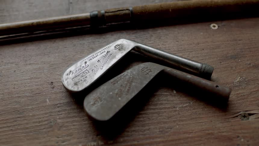 Golf club heads lying on a wooden table