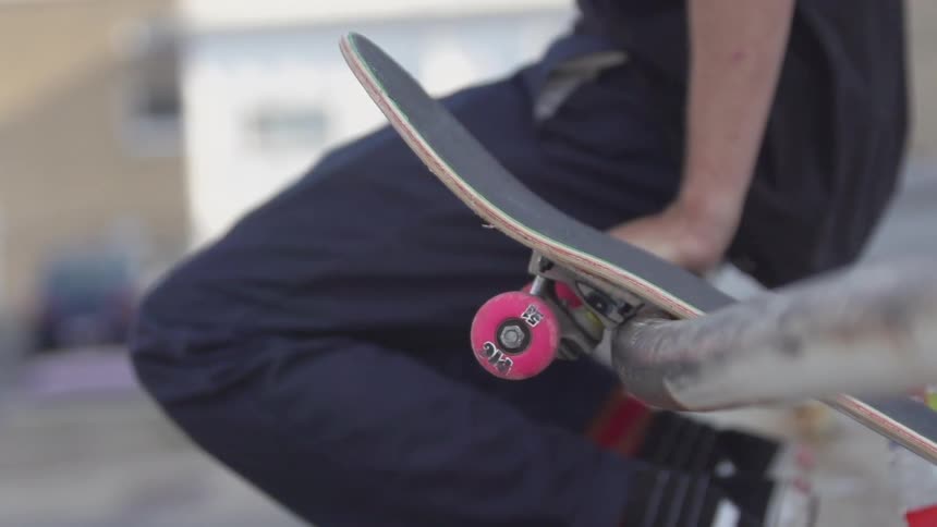 Person sitting on a railing with his skateboard by his side