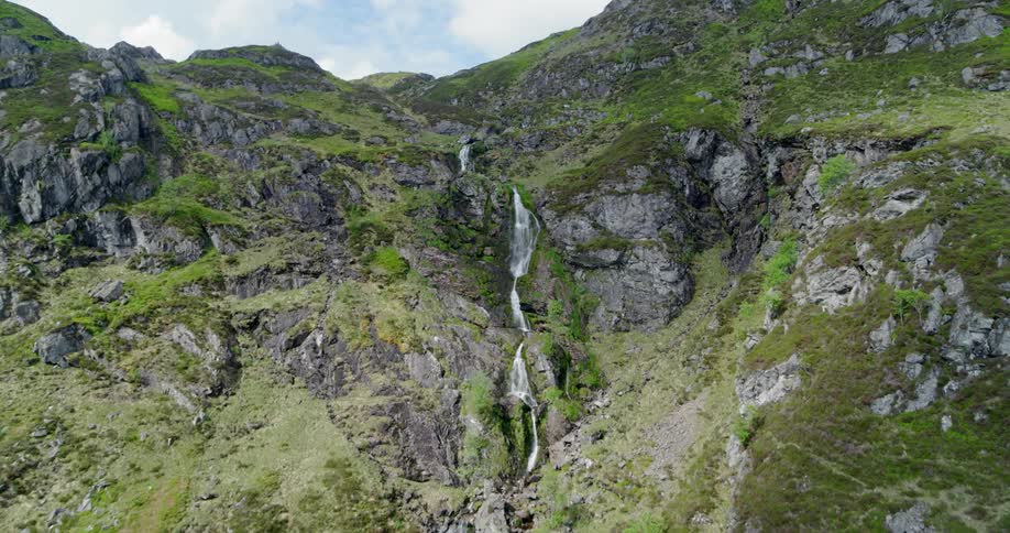 The mountains are tall with a waterfall running through the middle