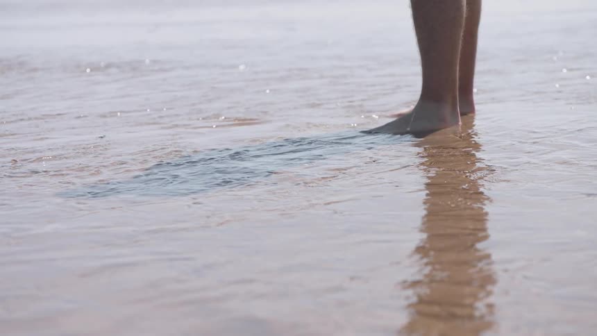 Person stands barefoot in shallow water
