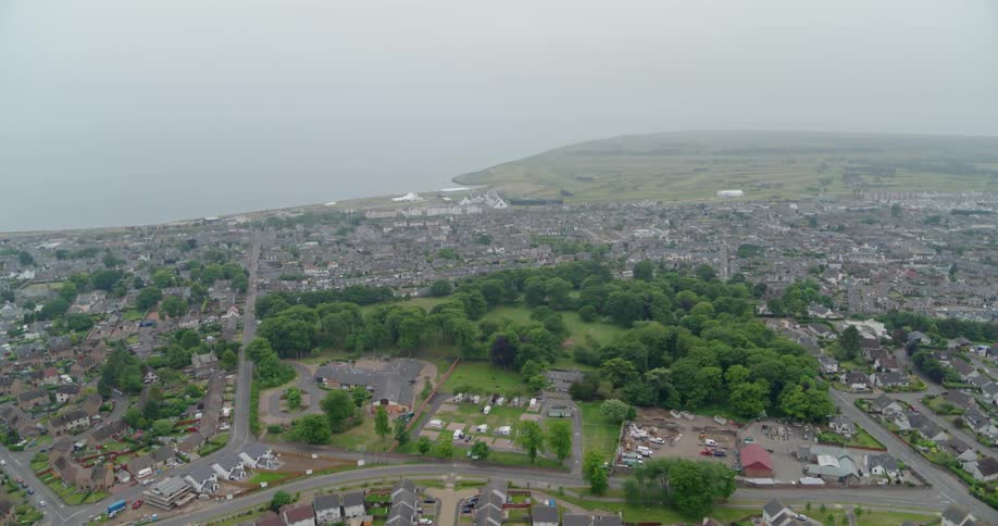 Fog and clouds are lingering over a coastal community during the day