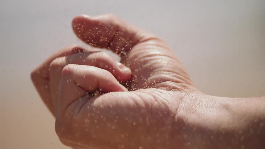Sand filters through a person's hand in the desert