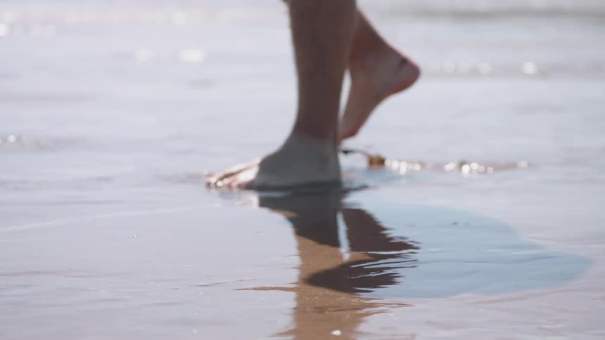 A person steps onto the wet sand on the beach