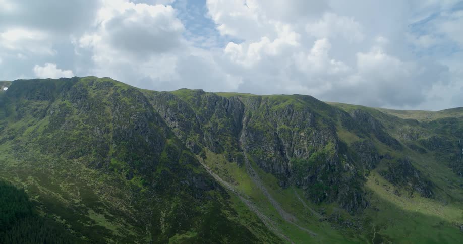 White and grey clouds hang above a tall mountain