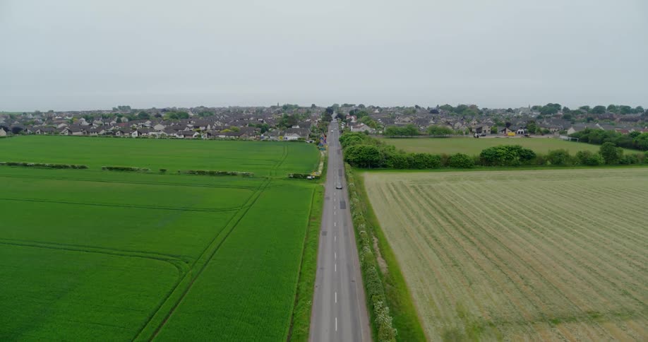 Road passes through grassy plains leading to a city