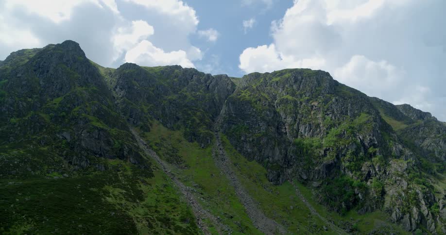 Trails go up a rocky and green mountain slope