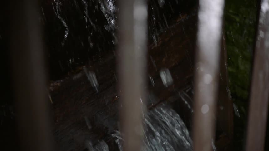 Water splashes off of a large wooden wheel