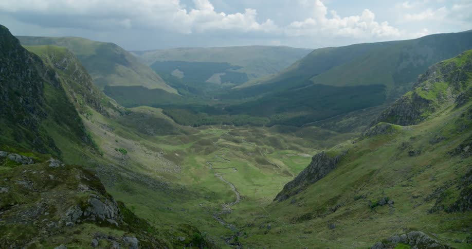 The valley is full of green mountains and a field below