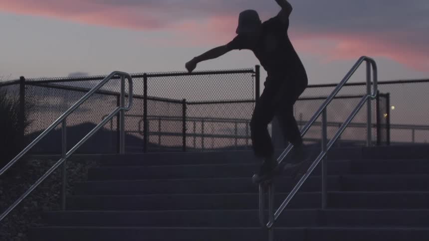 A skateboarder grinds a rail at dusk