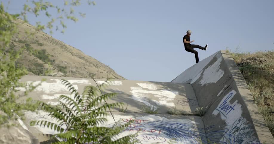 A white male falls while trying to skateboard up a concrete structure