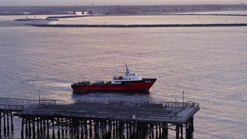 A boat is sailing off away from a pier at dusk