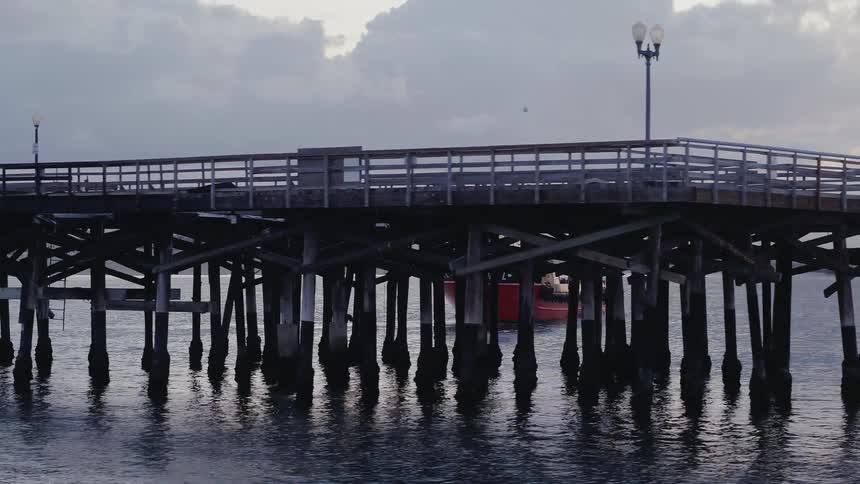 A boat is maneuvering close to a pier at dusk