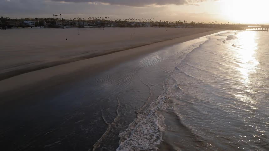 Waves are rolling onto a beach at dusk