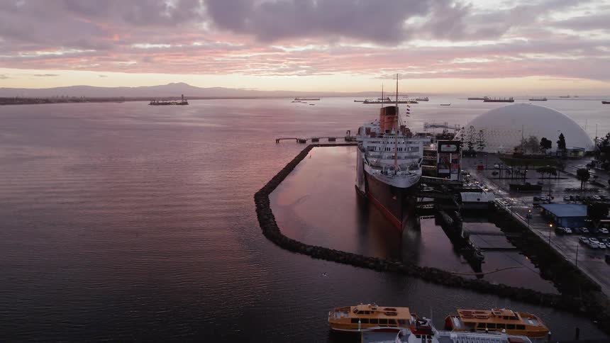 Yachts and ships are docked at sunset