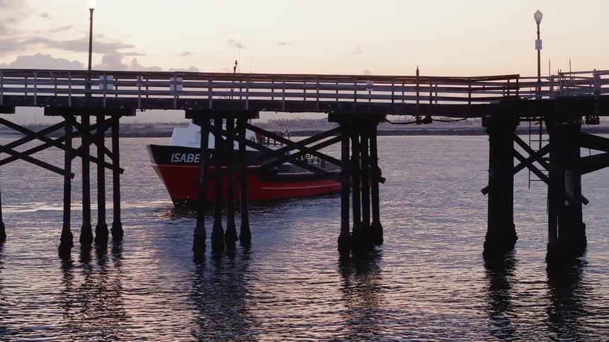 A boat is maneuvering close to a pier at dusk