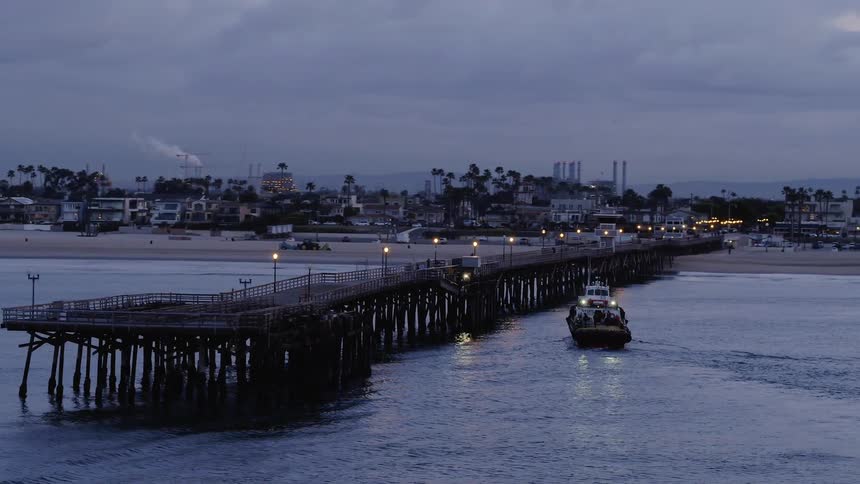 A boat floats next to an ocean pier