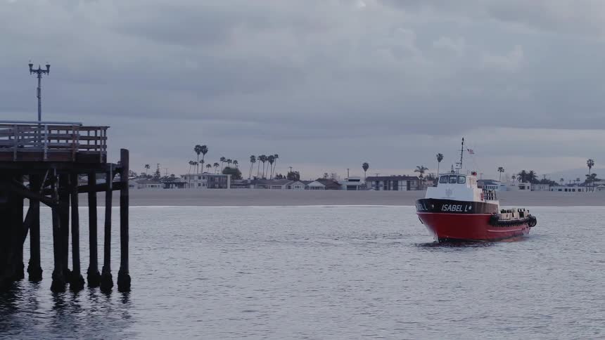 A boat is maneuvering close to a pier at dusk