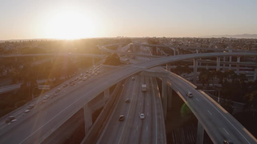Cars drive on a city freeway at sunset